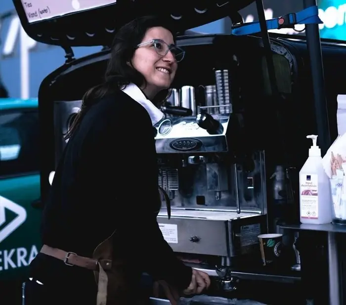 Smilende barista ved espressomaskinen i kaffevognen