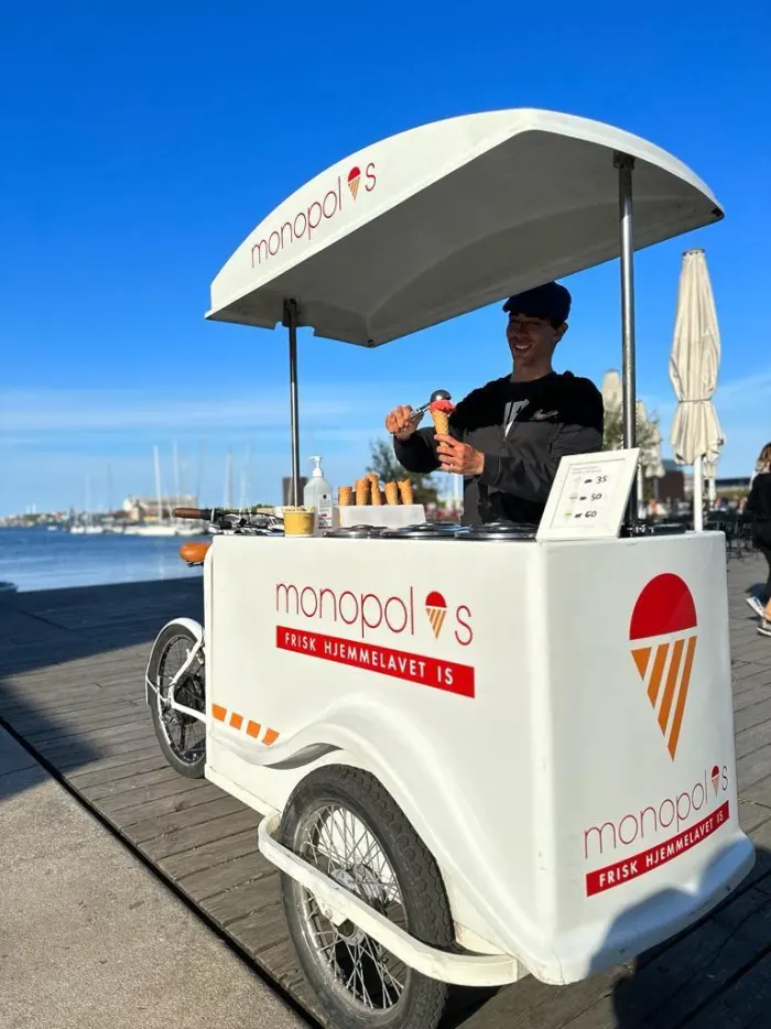 Medarbejder fylder en isvaffel ved isvognen på havnen