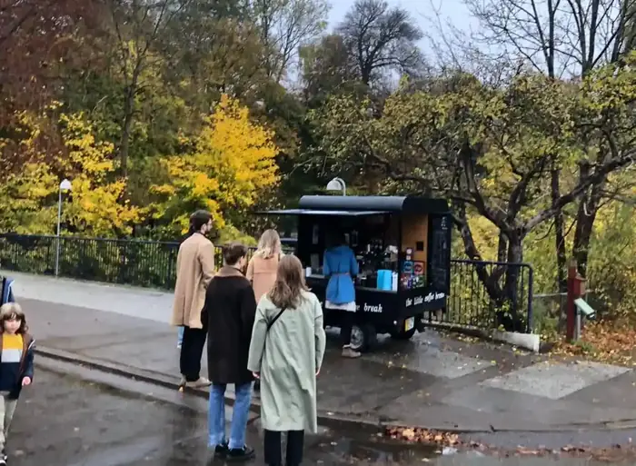 Gæster samlet om kaffevognen i en park om efteråret