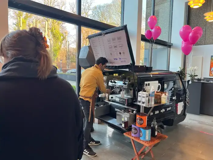 Barista serverer kaffe for gæster ved en indendørs reception