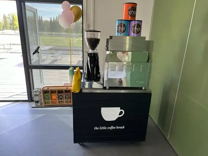 Lille mobil kaffebar med kværn og maskine opstillet på et kontor